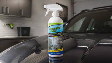 Mommy’s Glass 2-in-1 hard water spot remover and repellent bottle on a car hood in a garage